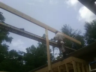 Carpenter setting a ridge beam over a new addition frame — Ice Dam Removal by Roofing Brothers in Ravenna