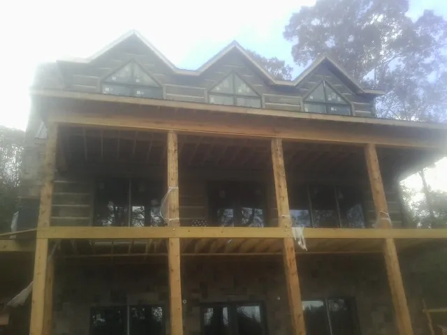 Dormers and porch framing on a large log home under construction — Roof Coating work by our crew in Ravenna