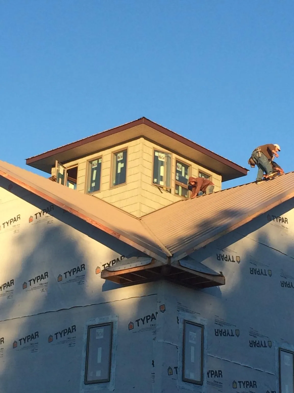 Roofers working around a rooftop cupola on a new metal roof at sunset — Roof Waterproofing in Ravenna by Roofing Brothers